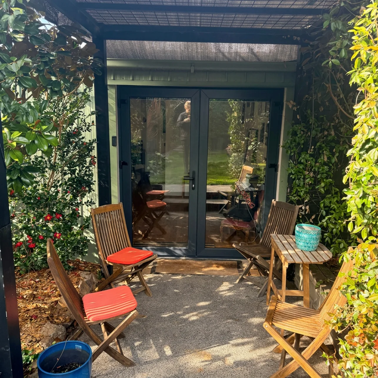 Private courtyard with timber folding chairs and a table outside the studio's glass doors